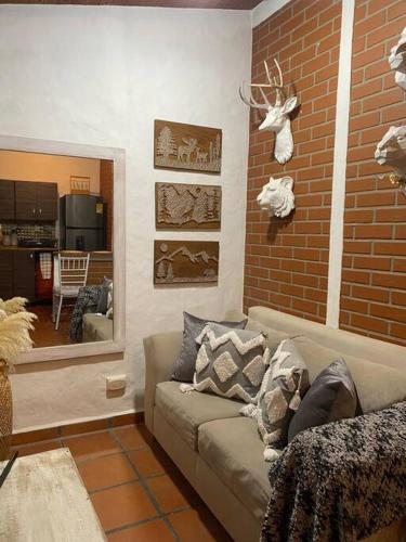 sala de estar con sofá y pared de ladrillo en Cabaña campestre en la Ceja, en La Ceja