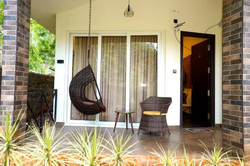 a porch with two chairs and a large window at Zeenath Taj Gardens in Yelagiri