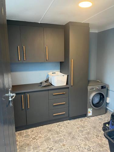 a kitchen with gray cabinets and a washing machine at 28 on Symonds luxstudio 6 for couples with solar backup in George