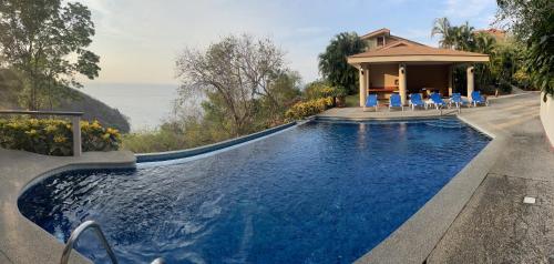 a swimming pool with chairs and a house at Bahia Pez Vela Resort in Ocotal