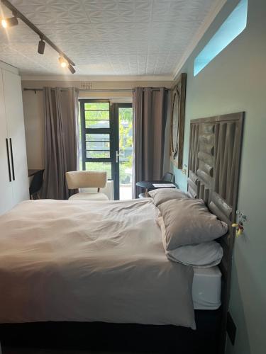 1 dormitorio con 1 cama grande y 1 silla en 28 on Symonds luxstudio 6 for couples with solar backup, en George