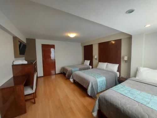 Habitación de hotel con 2 camas y escritorio en Miculla Hotel, en Tacna