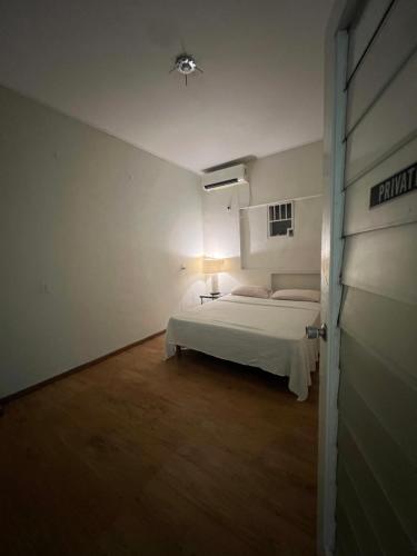 a white bedroom with a bed and a door at Dushi Apartments in Willemstad