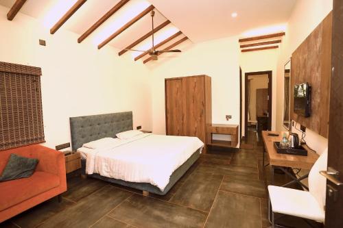 a bedroom with a bed and a desk and a couch at Zeenath Taj Gardens in Yelagiri