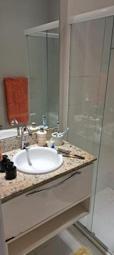 uma casa de banho com um lavatório e uma cabina de duche em vidro. em Maravilhoso 2 quartos na Praia de Itaparica - Vila Velha em Vila Velha