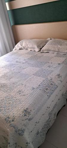 uma cama com um cobertor branco e uma parede verde em Maravilhoso 2 quartos na Praia de Itaparica - Vila Velha em Vila Velha