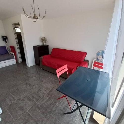 un salon avec un canapé rouge et une table dans l'établissement Barcarès - Studio à 50 m plage dans Village, au Barcarès