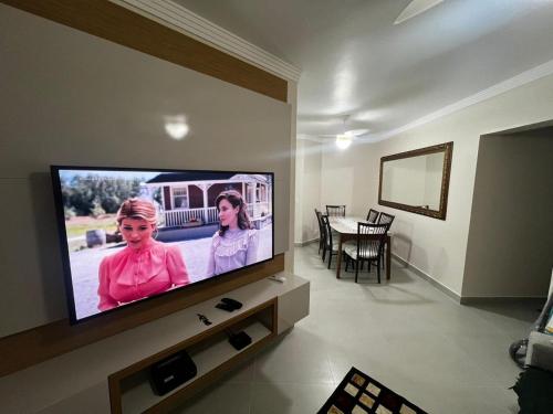 sala de estar con TV de pantalla plana en la pared en Apto 11 - Aconchegante - Praia da Enseada - Guarujá/SP, en Guarujá
