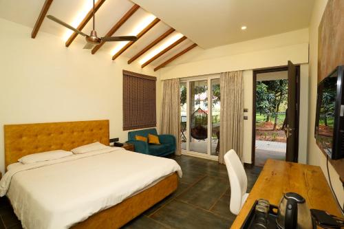 a bedroom with a bed and a table and a tv at Zeenath Taj Gardens in Yelagiri