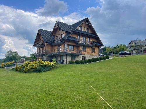 a large wooden house on a large grass field at Willa Rembisz in Łapsze Niżne