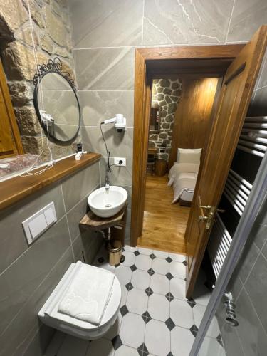 a bathroom with a sink and a toilet and a mirror at Hotel Ambassador Voskopojë in Voskopojë