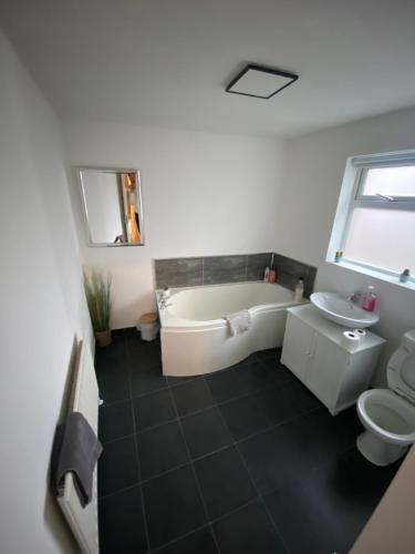 a bathroom with a tub and a toilet and a sink at House @ Queens University in Belfast