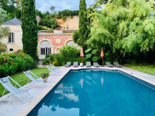 - une piscine avec des chaises et une maison dans l'établissement Le Gaimont Maison d'Hôtes Vouvray, à Vouvray