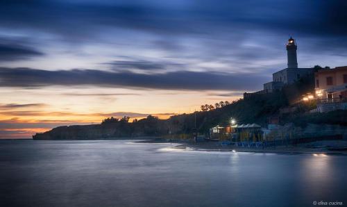 a view of a beach with a lighthouse at sunset at Casa Mariuccia in Anzio