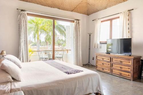 a bedroom with a bed and a flat screen tv at Casa La Columna in Puerto Vallarta