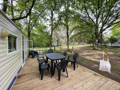 a patio with a table and chairs on a deck at Charmant Mobile Home en foret in Braize