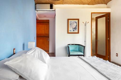 a bedroom with a white bed and a blue chair at Casa La Columna in Puerto Vallarta