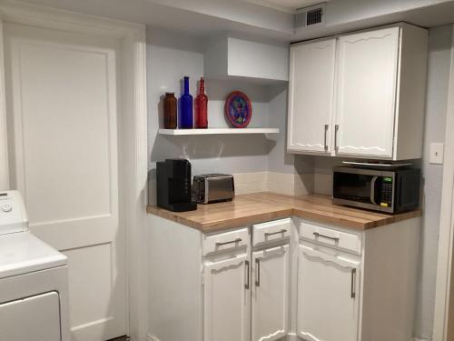 una cucina con armadi bianchi e bancone con forno a microonde di Guest Suite in Lafayette a Lafayette