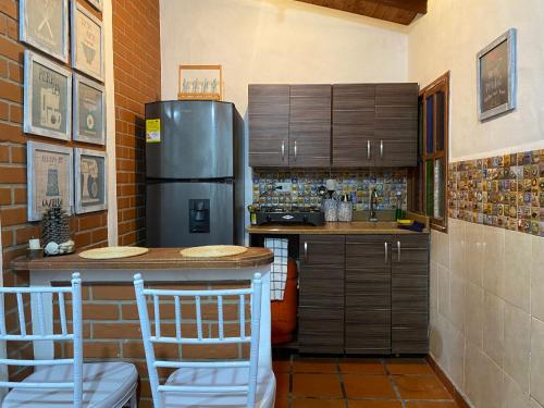 cocina con nevera y barra con sillas en Cabaña campestre en la Ceja, en La Ceja