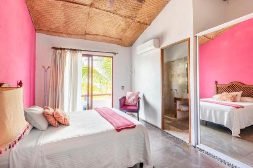 Habitación de color rosa con cama y espejo en Casa La Columna en Puerto Vallarta