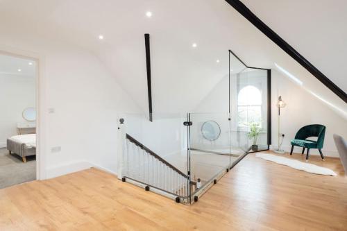 a white room with a staircase and a green chair at Spacious & Modern Two Bedroom Apartment in Catford, London in Catford