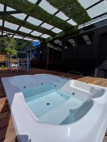 a jacuzzi tub on a deck with a roof at BusHotel Poás con Jacuzzi y Chimenea in Fraijanes
