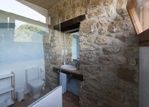 a stone bathroom with a sink and a toilet at Masoveria De Lladó in Llado
