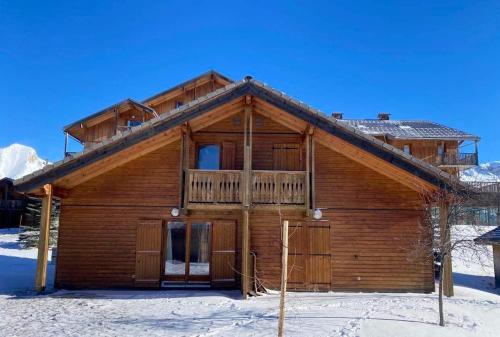 um chalé de madeira na neve com uma varanda em Chalet de 3 chambres a Le Devoluy a 200 m des pistes avec piscine partagee sauna et balcon em Le Dévoluy