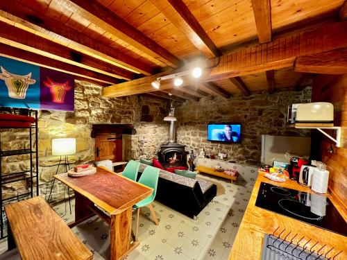 sala de estar con mesa y pared de piedra en La Cabaña María, en San Roque de Ríomiera