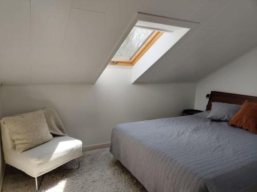 ein Schlafzimmer mit einem Bett und einem Stuhl im Dachgeschoss in der Unterkunft 3 Bedroom Duplex apartment in Helsinki