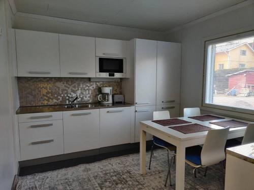 a kitchen with white cabinets and a table with chairs at 3 Bedroom Duplex apartment in Helsinki