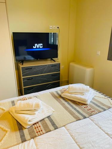 a bedroom with a tv and a bed with towels at NEW 2BD APRT with SHARED ROOFTOP POOL E2 in Athens