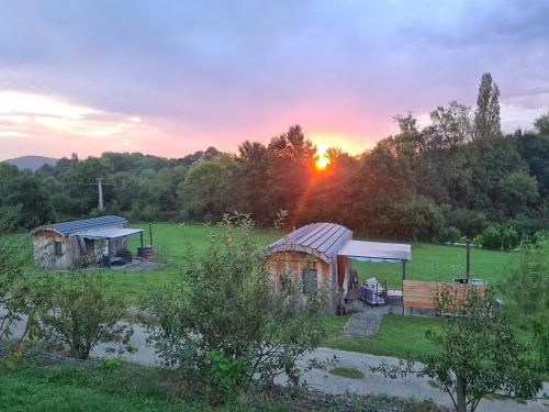 a group of huts in a field at sunset at Les Milles Bottes et ses Roulottes in Encausse-les-Thermes