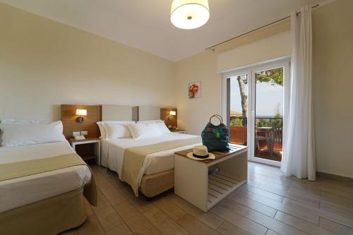 クロトーネにあるhotel villaggio Casarossaのベッド2台とバルコニーが備わるホテルルームです。