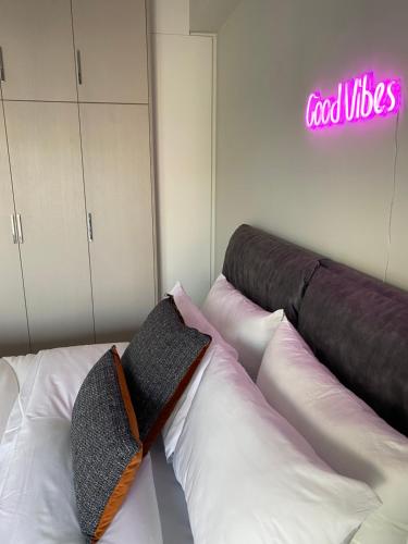 a room with a bed with pillows and a neon sign at NEW 2BDR apartment with SHARED ROOFTOP POOL in Athens