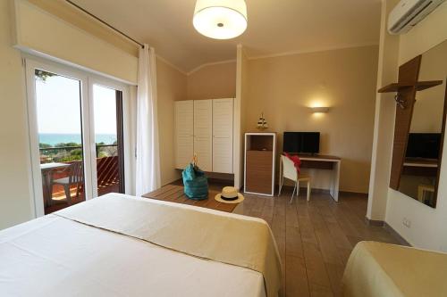 hotel villaggio Casarossa في كروتوني: غرفة نوم بسرير ومكتب وتلفزيون