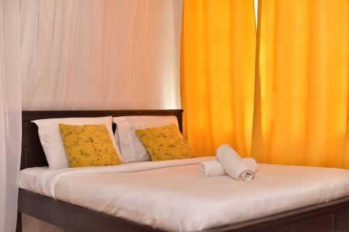 una camera con 2 letti con cuscini gialli e bianchi di The Carina Homes a Kisumu