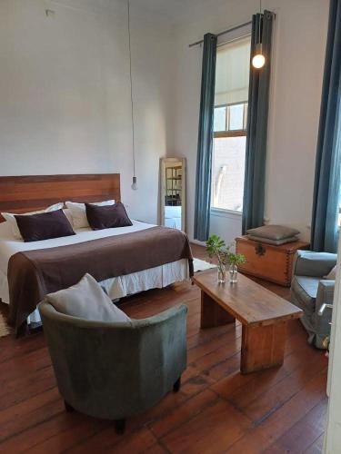 a bedroom with a bed and a chair and a table at Apartamentos Cerro Alegre in Valparaíso