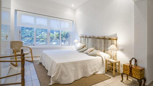 a white bedroom with a bed and a window at Cap Sa Sal 160 Begur in Begur