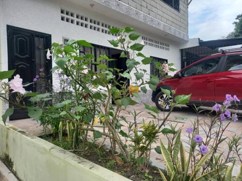a red car parked in front of a house with flowers at Apartamento moderno con AC y WiFi Ideal para grupos in Honda