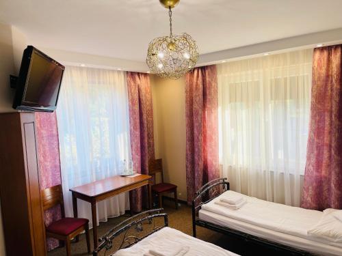um quarto com 2 camas, uma secretária e uma televisão em Pokoje noclegowe KASZTEL - Łowisko em Łowisko