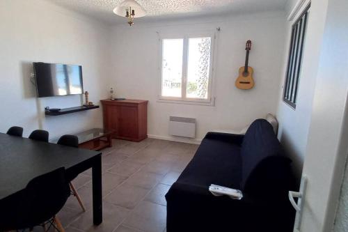 - un salon avec un canapé, une table et une guitare dans l'établissement Barcarès village - plage - mer - 4/9p+cour 3 étoil, au Barcarès