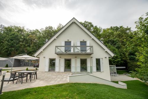 a white house with a patio and a table at Gátőr Villa in Mőcsény