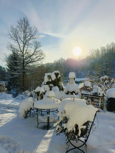 a picnic table covered in snow with the sun in the background at Apartament nad Potokiem in Piechowice