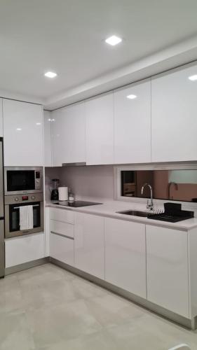 una cocina blanca con armarios blancos y fregadero en Up Sal en Aveiro