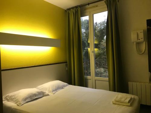 a bedroom with a bed and a window with at Hotel Couleurs Sud Centre-ville Gare Charleville-Mézières in Charleville-Mézières