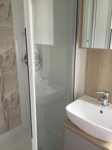 ein Badezimmer mit einem weißen Waschbecken und einer Dusche in der Unterkunft Lakeside Holiday Home in Hastings