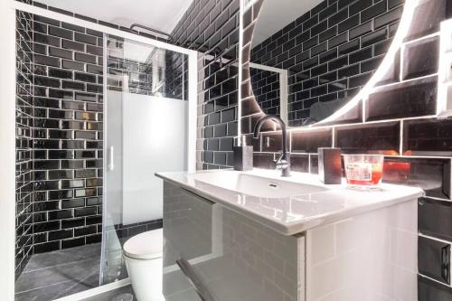 ein Badezimmer mit schwarzen Ziegelwänden und einem Waschbecken in der Unterkunft Acogedor alojamiento a pocos metros de la playa in Santa Pola