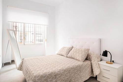 ein weißes Schlafzimmer mit einem Bett und einem Nachttisch in der Unterkunft Acogedor alojamiento a pocos metros de la playa in Santa Pola