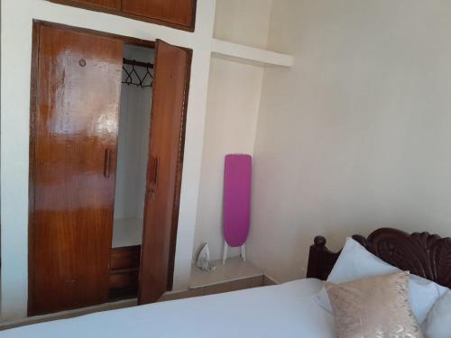 sypialnia z łóżkiem i drewnianymi drzwiami w obiekcie Galene Abode Studio Apartment, Nyali w mieście Mombasa
